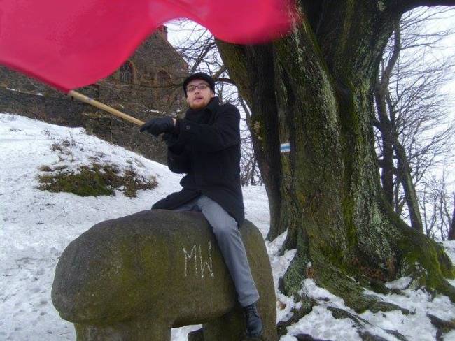 Pupka na kamiennym niedźwiedziu, z czerwoną flagą.